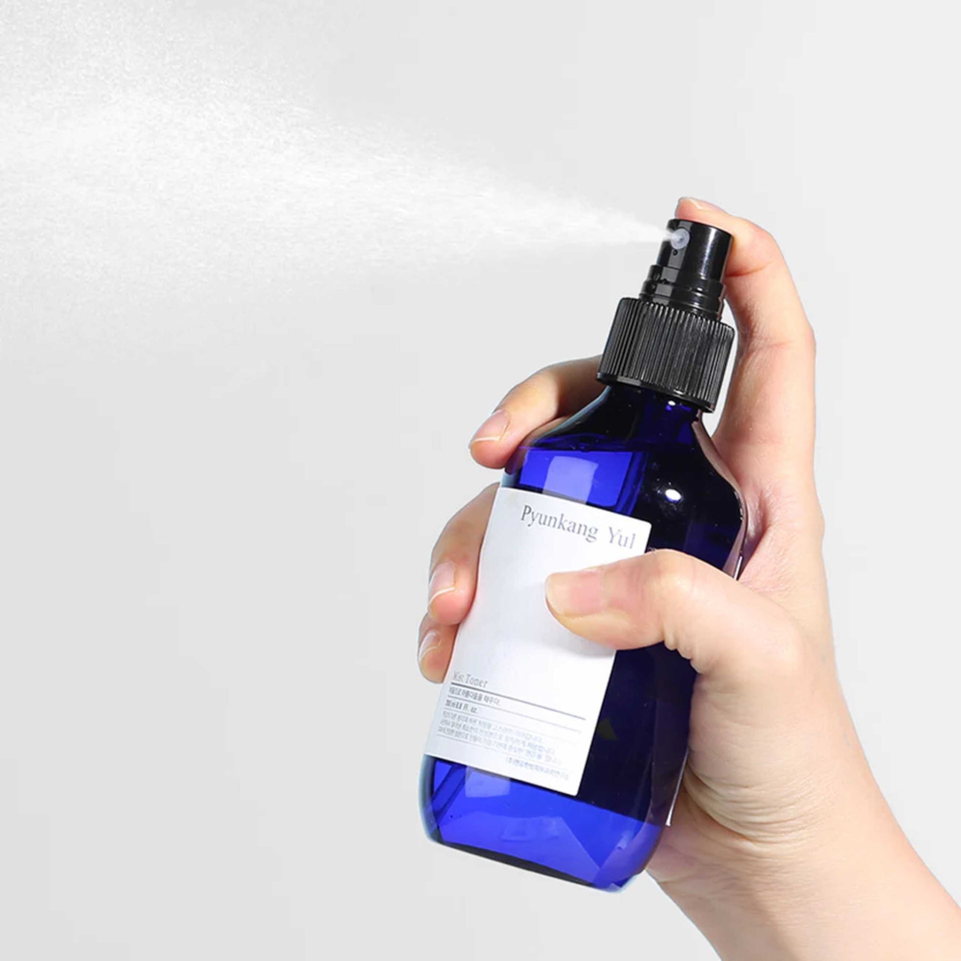 Pyunkang Yul Mist Toner sprayes på hånd fra blå flaske