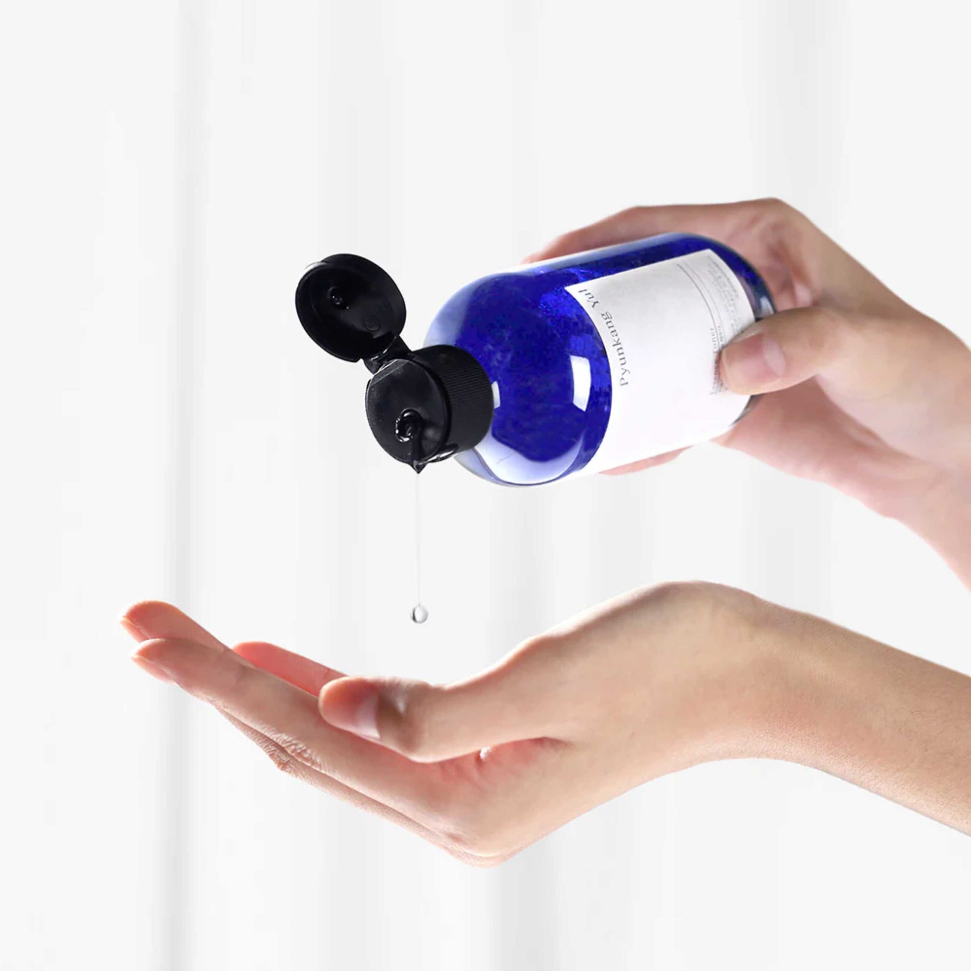Pyunkang Yul Essence Toner påføres i hånd fra blå flaske