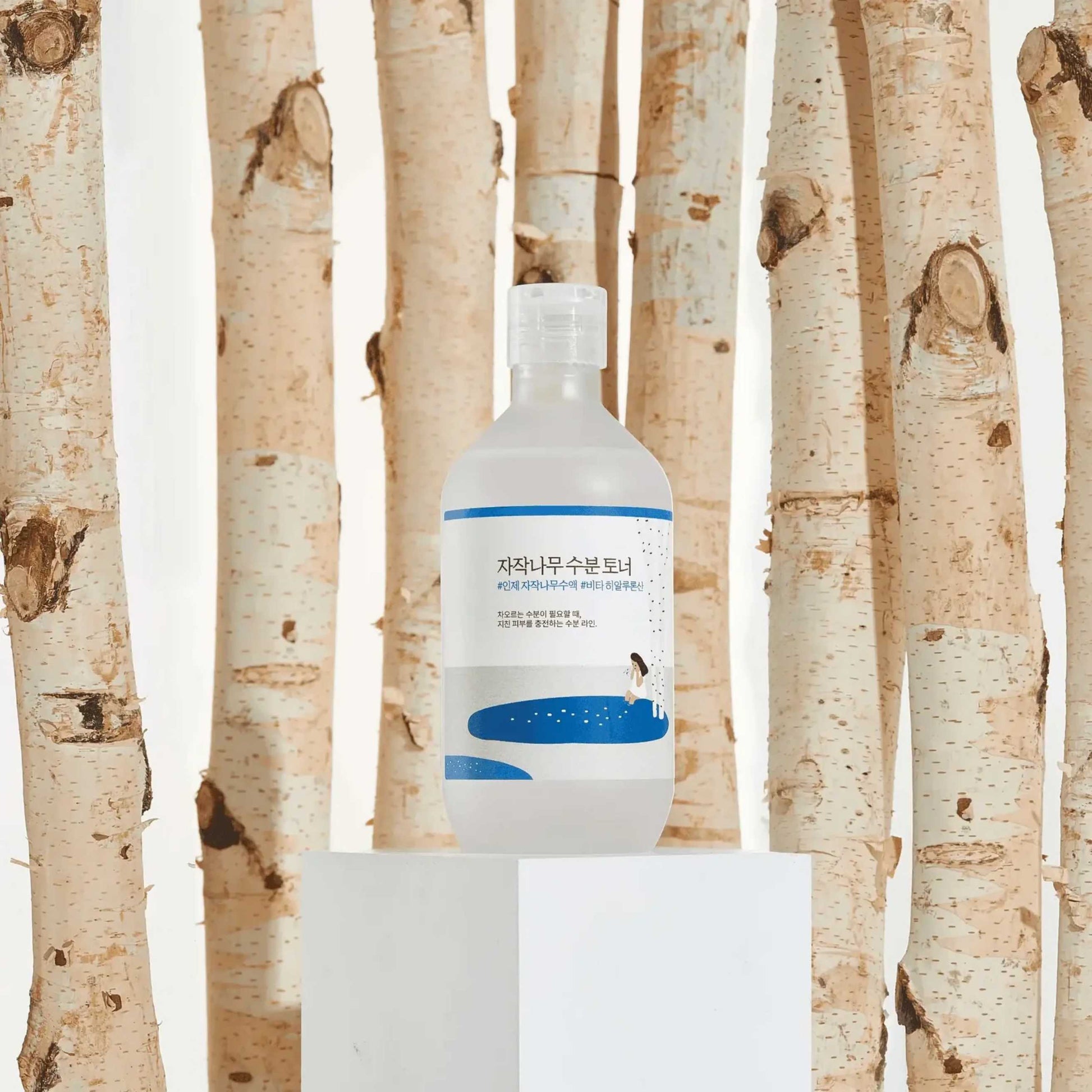 Round Lab Birch Juice toner med bjørketrær i bakgrunn